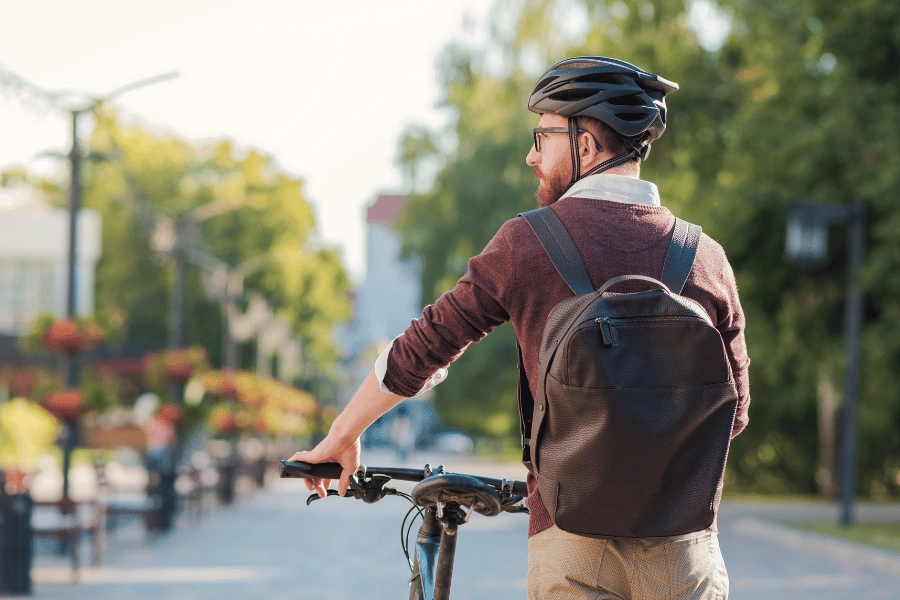 man wearing a helmet and backpack biking to work in the city
